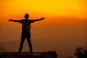 Fototapeta na wymiar Man tourist on the cliff of the mountain on sunset background