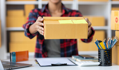 Young African woman starting an online shopping business from home is preparing packages to deliver...