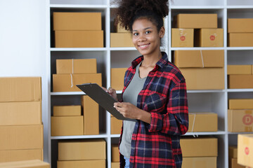 Young African woman starting an online shopping business from home is preparing packages to deliver...