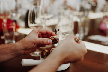 Man eating escargots with special fork while enjoying dinner in restaurant during vacation