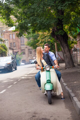 Happy young couple by a vintage scooter on the street