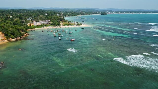 Aerial view over tranquil azure ocean lagoon dotted with fishing boats near tropical beach. Tourism destination for vacation, aerial footage for nature documentary, perfect for travel agency promo. - Powered by Adobe