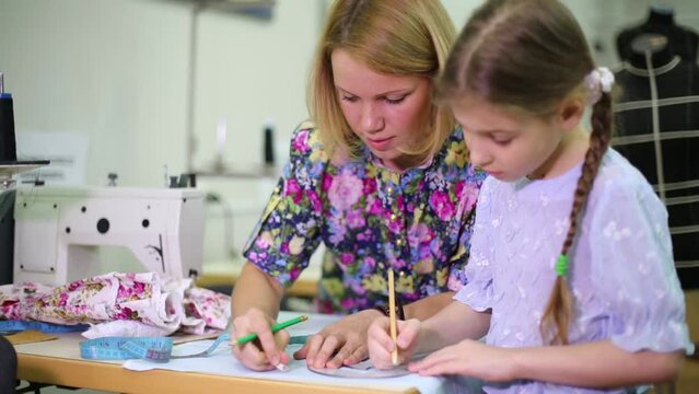 tailor teaches student girl use of templates near sewing machine