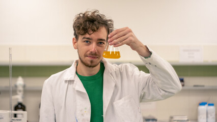 Chemist in the lab looking at chemicals and smiling