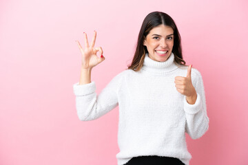 Young Italian woman isolated on pink background showing ok sign and thumb up gesture