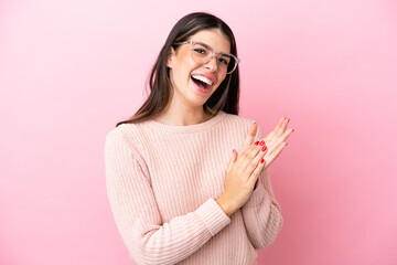 Young Italian woman isolated on pink background With glasses and applauding