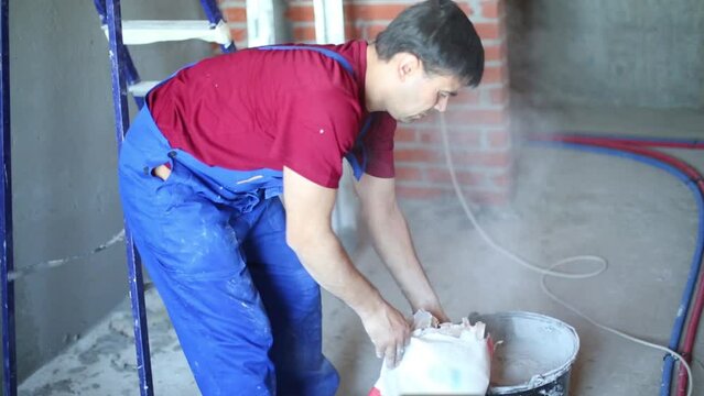 Legs of worker preparing concrete grout for plaster wall