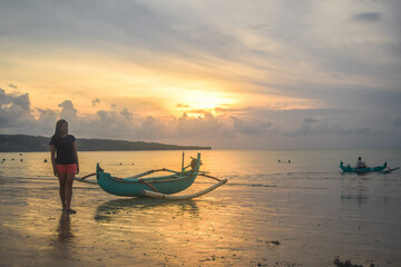 a woman standing alone  enjoy the sunset at kuta beach