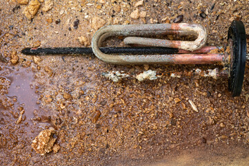 Heating element of an electric water heater with a rusty anode and a tube covered with scale, a...