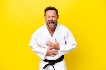 Middle age caucasian man doing karate isolated on yellow background smiling a lot
