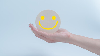 Customer service evaluation and satisfaction survey concepts. The client's hand holding  the happy face smile face icon on circle wood