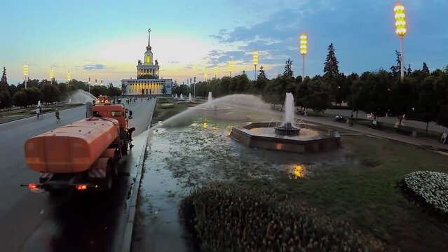 Watering of flowerbeds from truck with cistern at spring evening in All Russia Exhibition Center. Aerial view