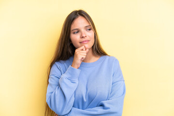 Young caucasian woman isolated on yellow background and looking up
