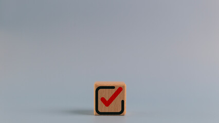 Wooden cube with a checkmark icon. Goals achievement and business success. Task completion. Ethical corporate. Do the right thing. Quality and ISO symbol.