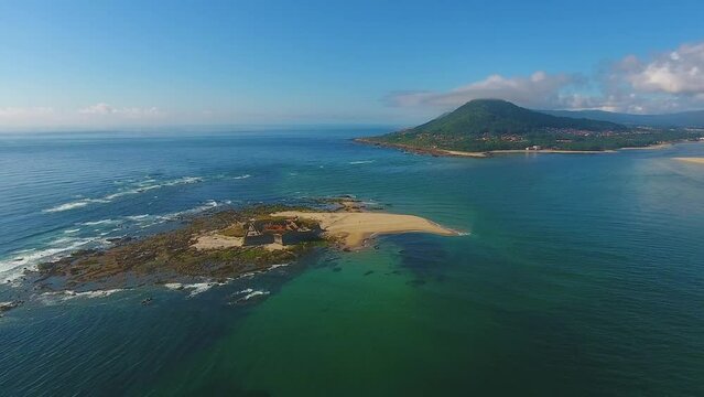 Aerial shot of an island in the middle of the ocean near the mainland in Moledo do Minho, Caminha, Portugal.