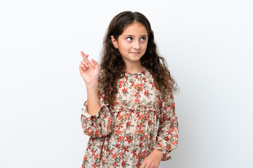 Little caucasian girl isolated on white background with fingers crossing and wishing the best