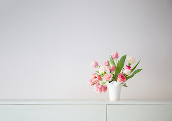 pink spring flowers in white ceramic vase in modern home interior