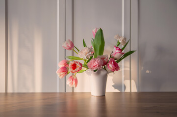 pink spring flowers in white ceramic vase in modern home interior
