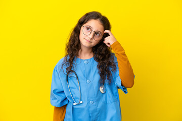 Little nurse girl isolated on yellow background having doubts and with confuse face expression