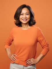 Portrait of a middle aged filipino elegant woman smiling happily. Orange background