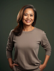 Middle aged filipino businesswoman posing confidently and smiling. Studio portrait on grey background 