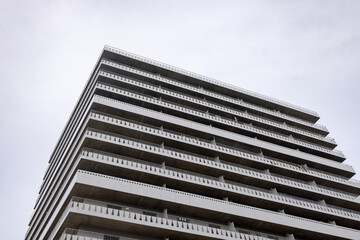 Fototapeta na wymiar A high-rise apartment building with terraces on a gray sky background. Copy the space