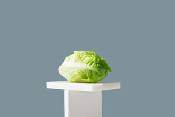 Corazón de lechuga romana fresca sobre un soporte blanco y fondo verde	