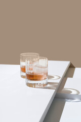 Dos vasos de whisky con hielo sobre un fondo marrón