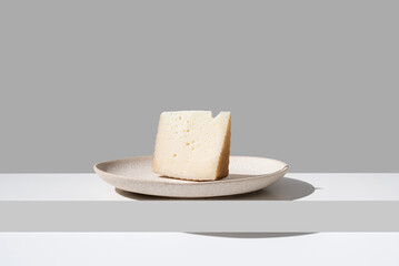 Trozo de queso de oveja curado. Cuña de queso manchego sobre fondo gris	