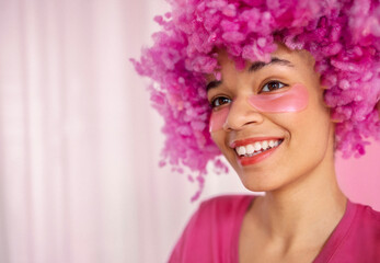 Close up of portrait of attractive happy darkskinned girl with soft pink curly wig.