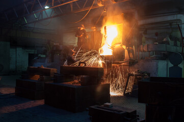 Industrial workers at a foundry pour molten metal with sparks. Teamwork in heavy industry, manufacturing process. Protective gear for safety. Hot steel casting, metalwork factory interior.