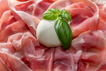 Sliced parma ham with mozzarella cheese and basil leaves, full frame background.