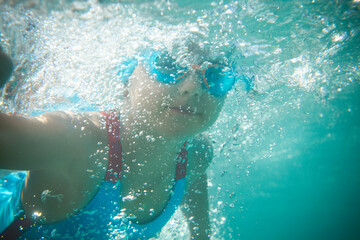 Little girl swims in the pool underwater