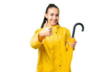 Young Arabian woman with rainproof coat and umbrella over isolated chroma key background with thumbs up because something good has happened