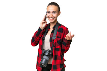 Young photographer Arab woman over isolated background keeping a conversation with the mobile phone...