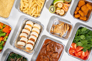 Batch Cooking Meal Prep concept. Several types of side dishes: cereals, pasta, pasta, cooked and fresh vegetables, meat, chicken, nuggets, breakfast pancakes and fruit in food containers 