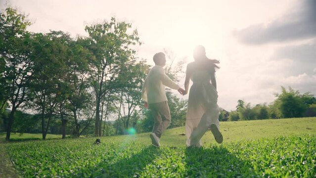 Back rear asia people young adult man woman falling in love flirt hold hand follow run at nature park enjoy fun date day. Summer joy sun light happy asian lover bride groom just married sweet newlywed