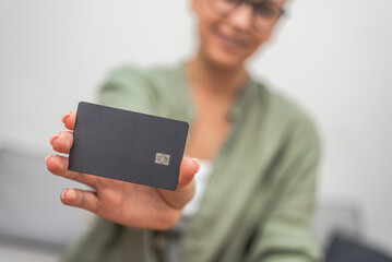A lady's hand holds a dark credit card with a chip, perfect for contactless payments, exemplifying...