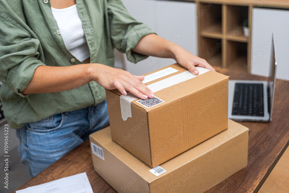 Poster seamlessly connected: woman's hands apply a qr code sticker to a package, showcasing the essence of 