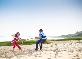 Tug of war - boy and girl playing on the beach