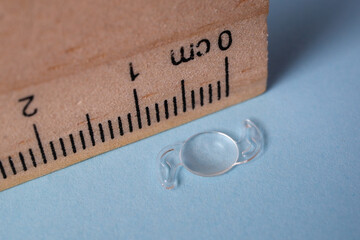 photo of foldable itraocular lens IOL for treating cataract beside wooden ruler