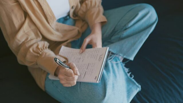 Hands, writing in notepad and person in home on sofa for creative idea, planning and schedule agenda. Inspiration, notes and closeup on couch with journal, to do list and pen to study in living room