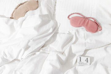 14 february background, holiday date on calendar in bed with eye sleep mask on white cotton sheets....
