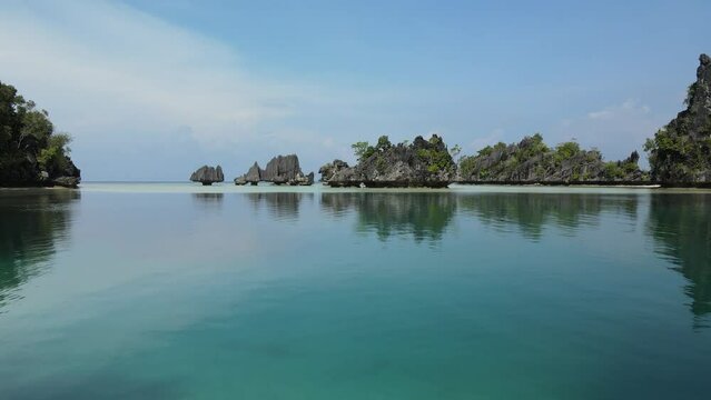 aerial shoot, flight over colourful lagoon with Turquoise water, sand beach and palm trees in Raja Ampat Indonesia