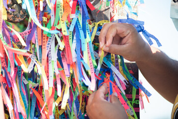 Catholics are seen tying ribbons on the railing of the Senhor do Bonfim church during an open mass...