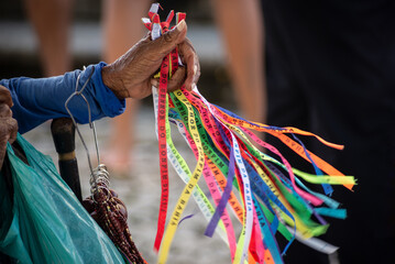 Hands of a street vendor holding souvenir ribbons during open mass at the Senhor do Bondim church...
