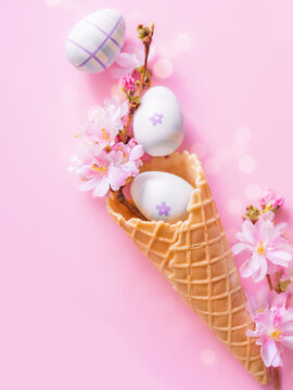 Creative Easter vertical photo with bokeh. Easter eggs and pink flowers in a waffle cone for ice cream. Happy and joyful Easter. Church Christian holidays, Christianity