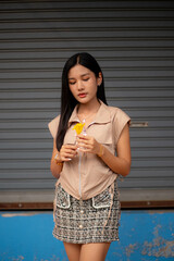 A young woman dressed in vintage clothes holds a yellow flower and admires it in her hand.