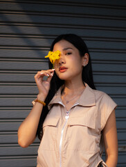 A young woman dressed in vintage clothes holds a yellow flower and admires it in her hand. and turned to look at the camera