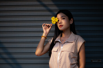 A young woman dressed in vintage clothes holds a yellow flower and admires it in her hand. and turned to look at the camera
